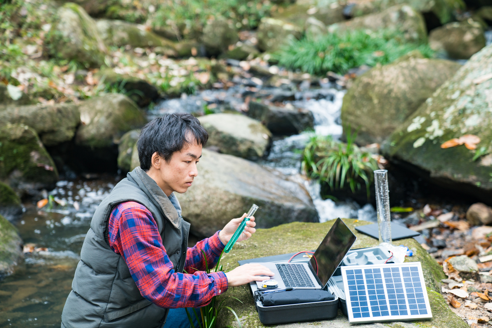 An environmental researcher monitoring water quality from a solar powered field laboratory
